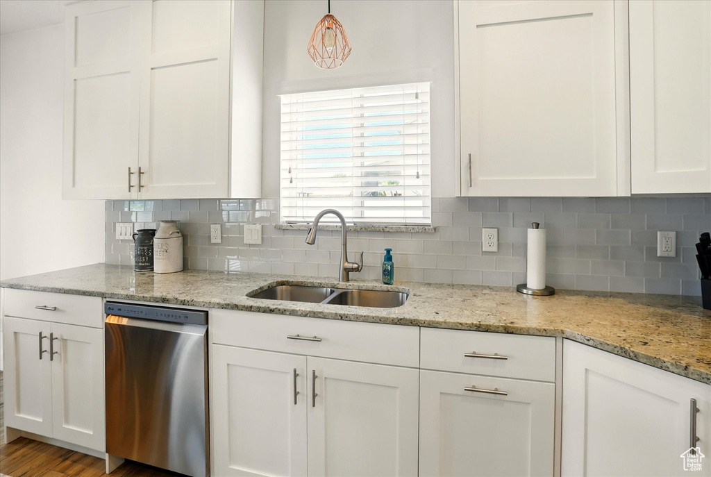 Kitchen with stainless steel dishwasher, a sink, and white cabinetry