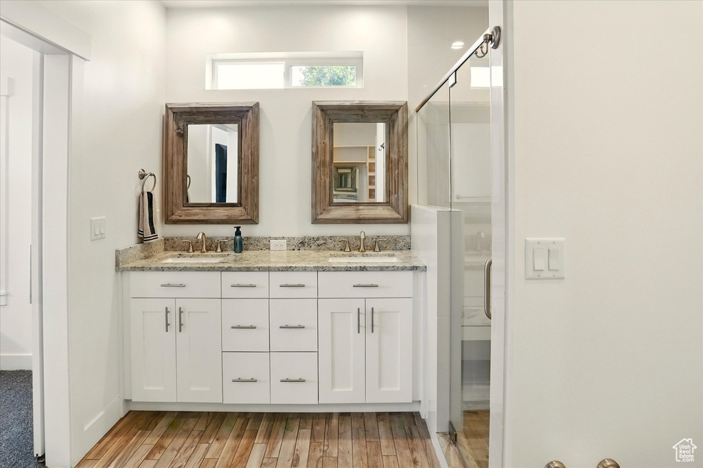 Bathroom featuring double vanity, wood finished floors, and a shower with shower door