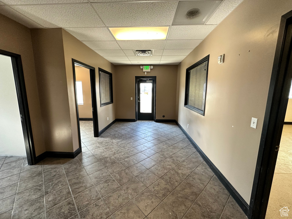 Empty room featuring a drop ceiling, tile patterned floors, and baseboards