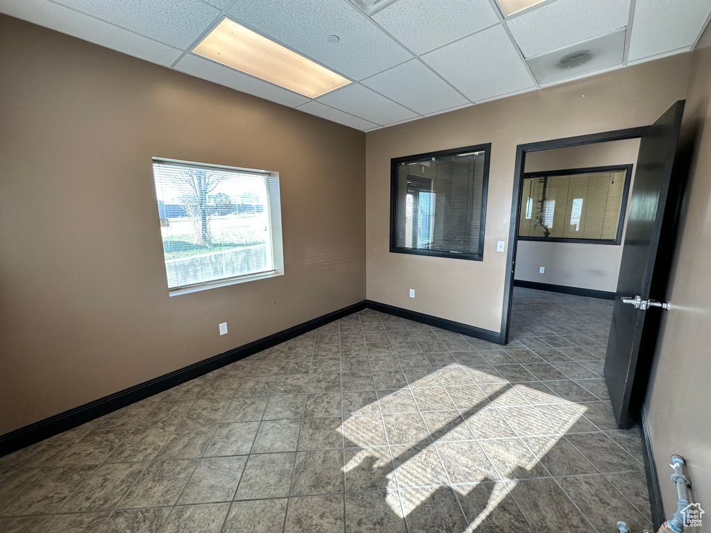 Tiled spare room featuring a paneled ceiling and baseboards