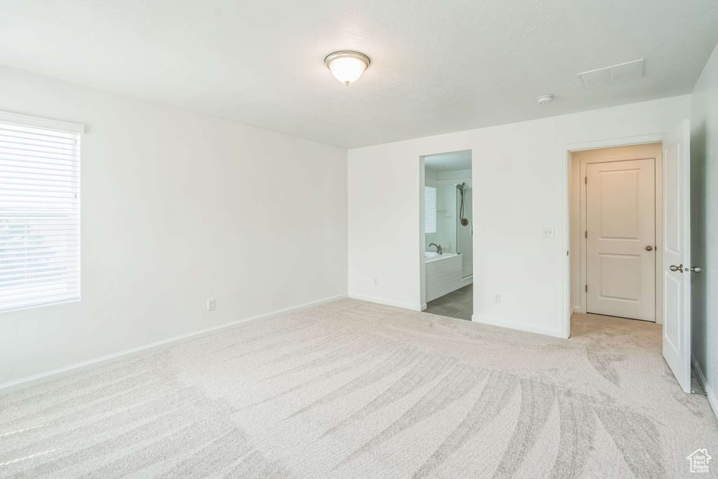 Unfurnished bedroom with light colored carpet and ensuite bathroom