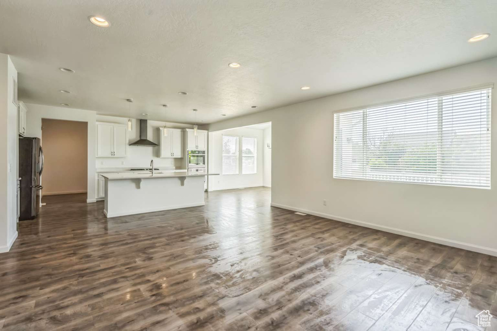 Unfurnished living room featuring dark wood-style flooring and recessed lighting