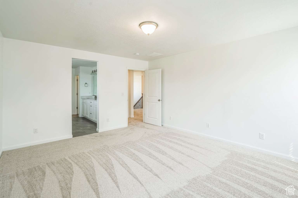 Unfurnished bedroom featuring light colored carpet and connected bathroom