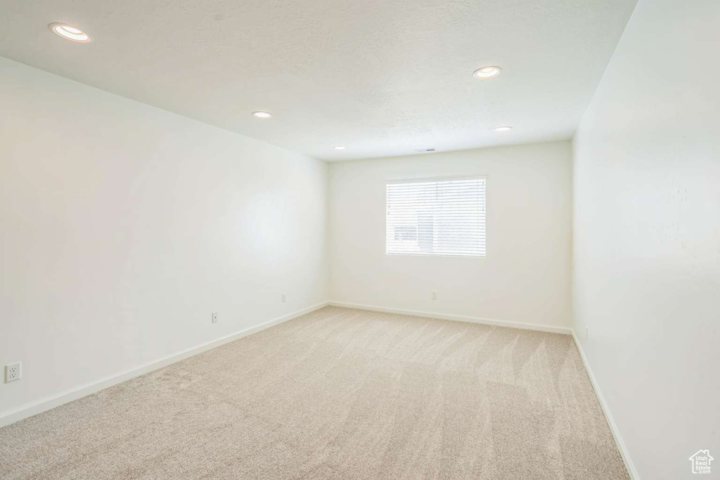 Empty room with light colored carpet and recessed lighting