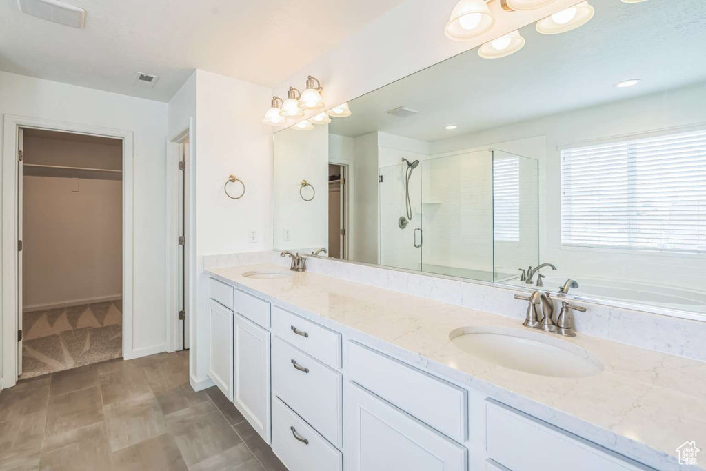 Bathroom with a spacious closet, a stall shower, double vanity, and a bath