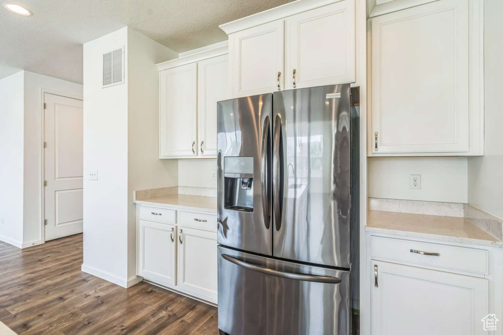 Kitchen featuring stainless steel fridge, dark wood-style floors, white cabinets, and recessed lighting