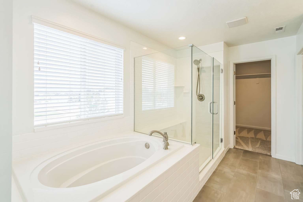 Full bathroom featuring a garden tub, a stall shower, and a spacious closet
