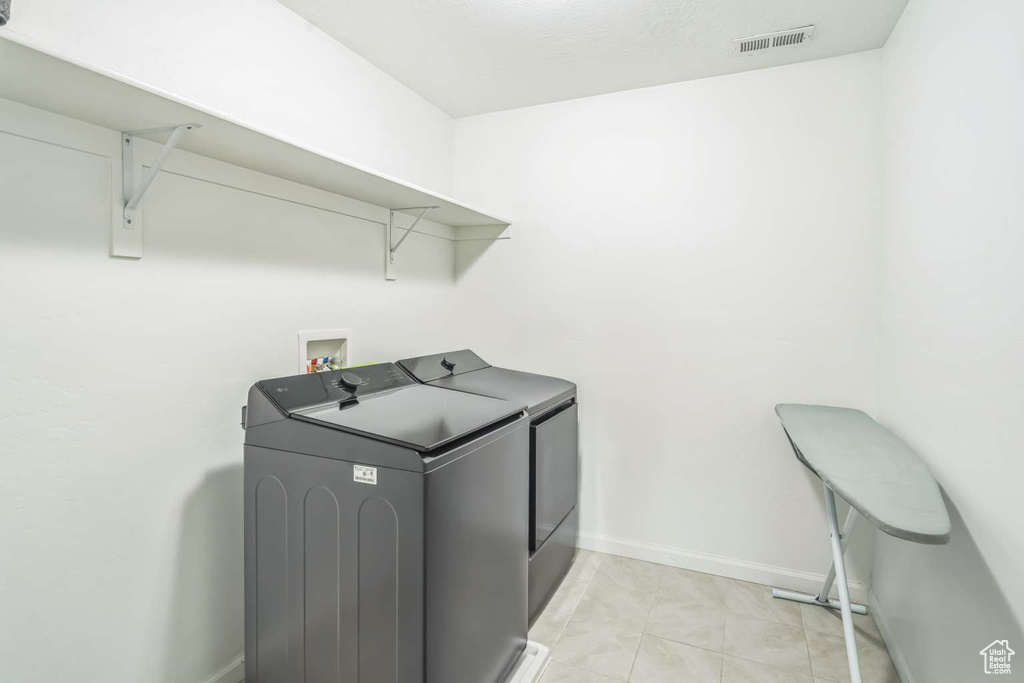 Laundry room with independent washer and dryer and light tile patterned floors
