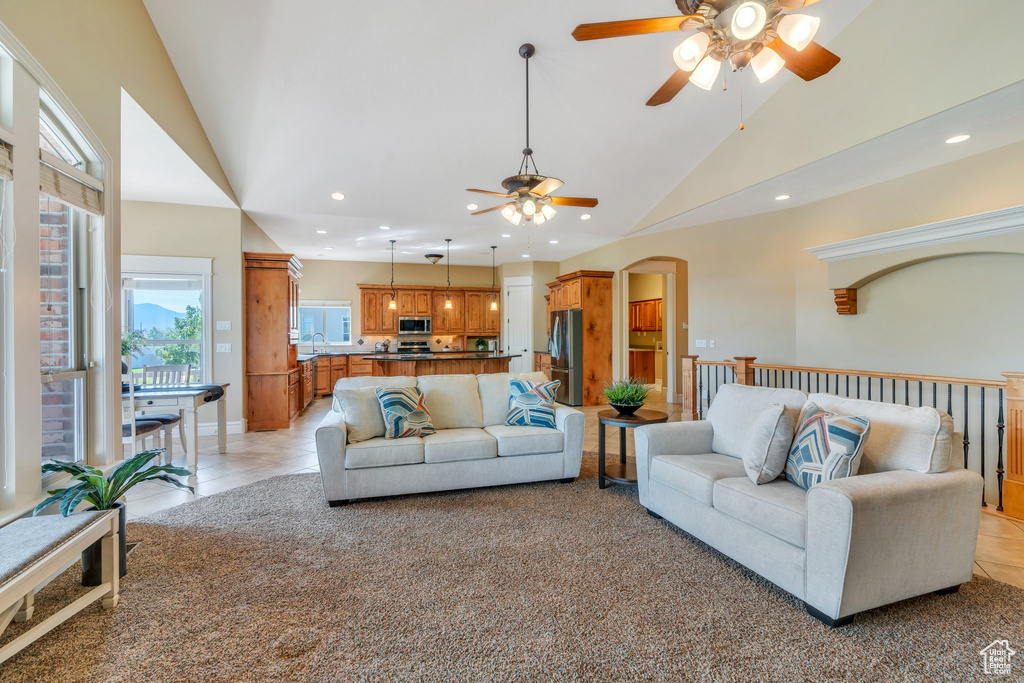 Living area featuring ceiling fan, recessed lighting, arched walkways, light tile patterned flooring, and high vaulted ceiling