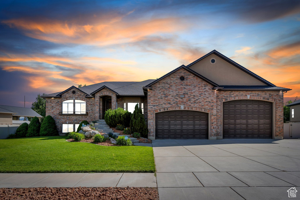French country style house featuring driveway, a front lawn, a garage, and brick siding
