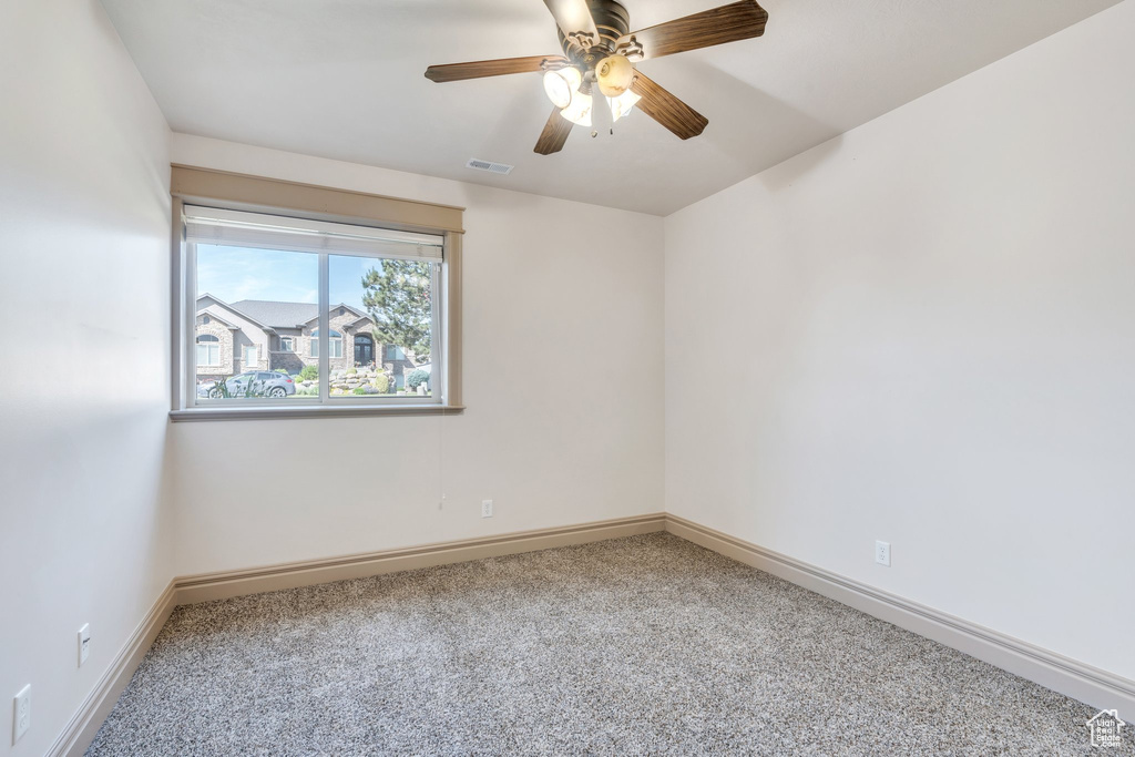 Carpeted empty room featuring baseboards and ceiling fan