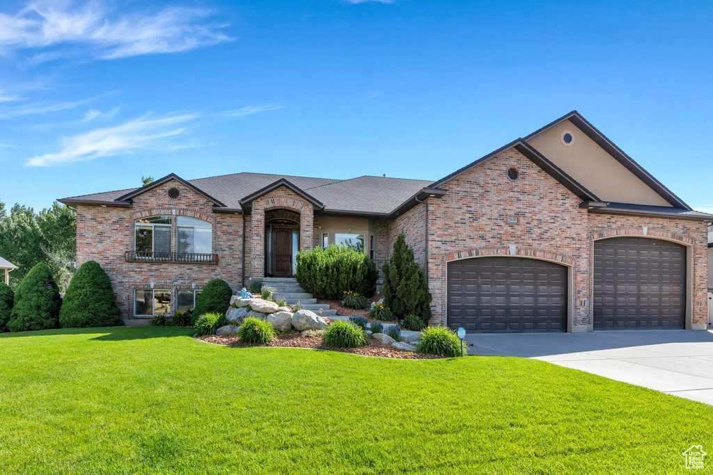 French country inspired facade with a front yard, brick siding, a garage, and driveway