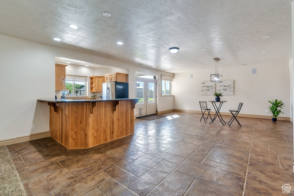 Kitchen with freestanding refrigerator, recessed lighting, baseboards, a peninsula, and a kitchen breakfast bar