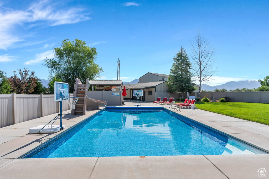 View of swimming pool featuring a water slide, a patio area, and a mountain view