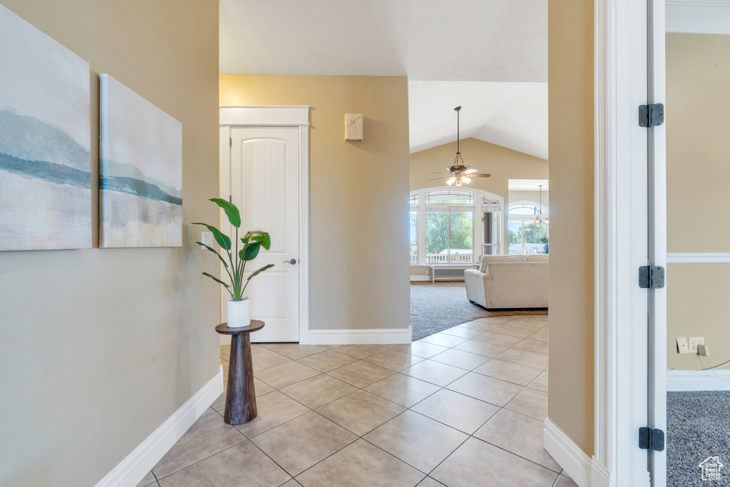 Foyer entrance featuring vaulted ceiling, a ceiling fan, light tile patterned floors, and baseboards