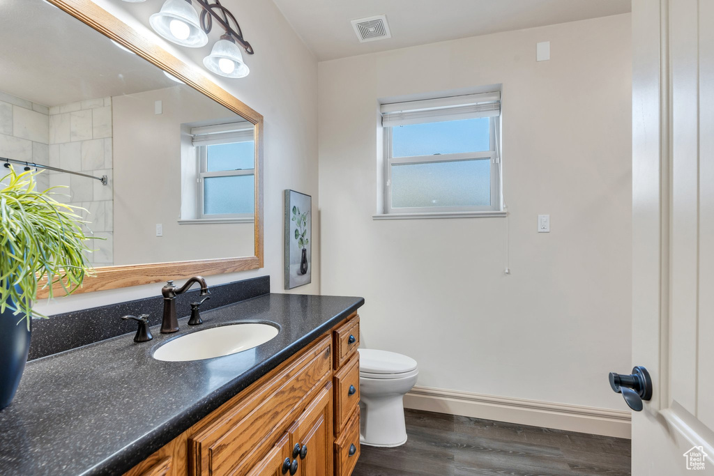 Bathroom with toilet, wood finished floors, vanity, a shower with curtain, and baseboards