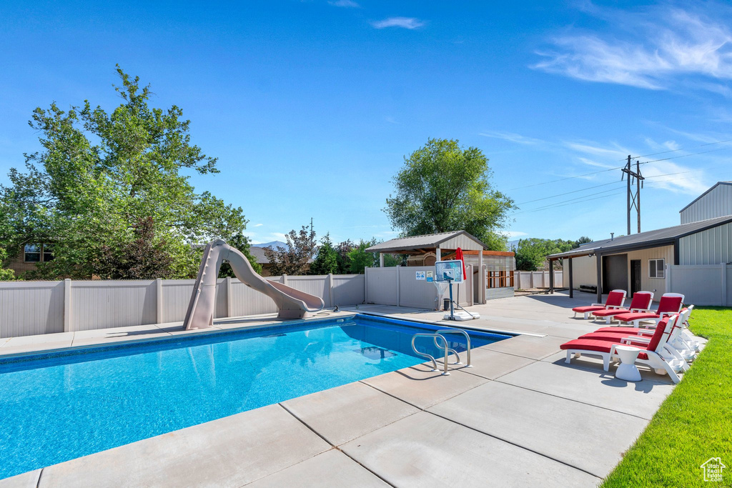 View of pool featuring a patio area, a water slide, and a fenced backyard