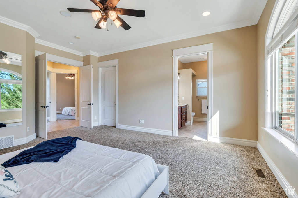 Bedroom with light colored carpet, ornamental molding, baseboards, connected bathroom, and a ceiling fan