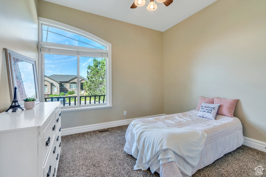 Carpeted bedroom with baseboards, multiple windows, and a ceiling fan