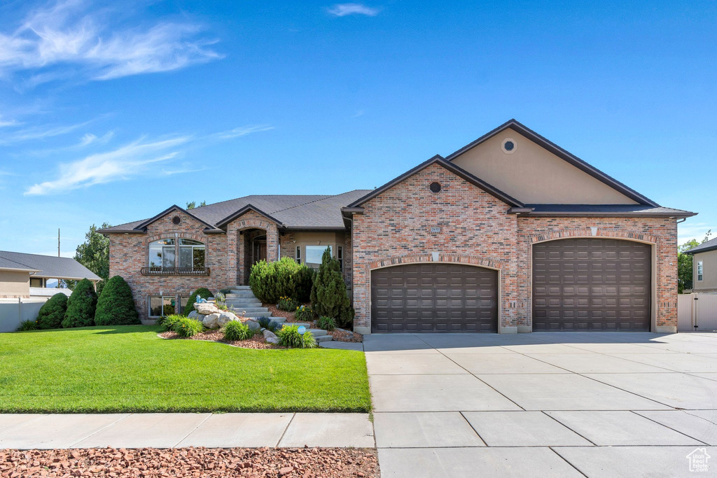 French country home with a front lawn, concrete driveway, a garage, and brick siding