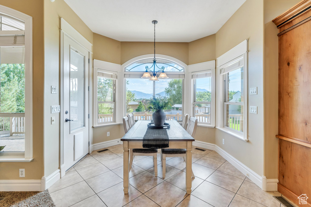 Dining space featuring a chandelier, light tile patterned flooring, and baseboards