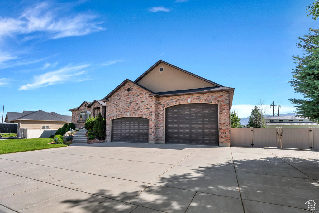 View of front facade with concrete driveway, a gate, an attached garage, and brick siding
