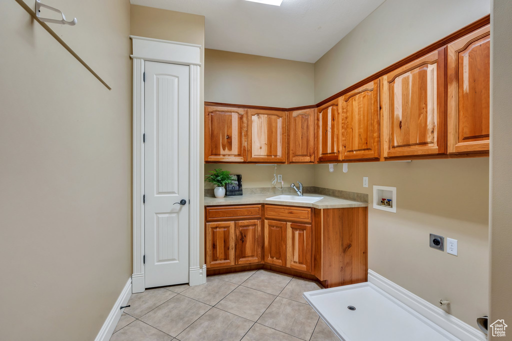 Laundry area with electric dryer hookup, hookup for a gas dryer, cabinet space, washer hookup, and light tile patterned floors