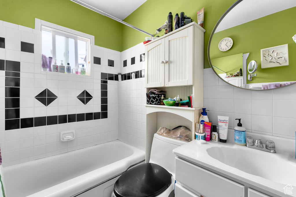 Bathroom with vanity,  shower combination, toilet, and tile walls