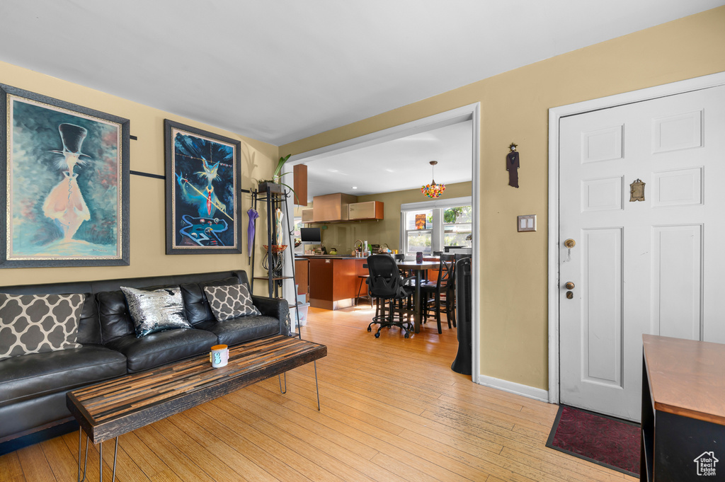 Living area featuring light wood-type flooring, a chandelier, and baseboards