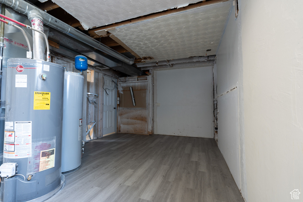 Unfinished basement featuring water heater and wood finished floors