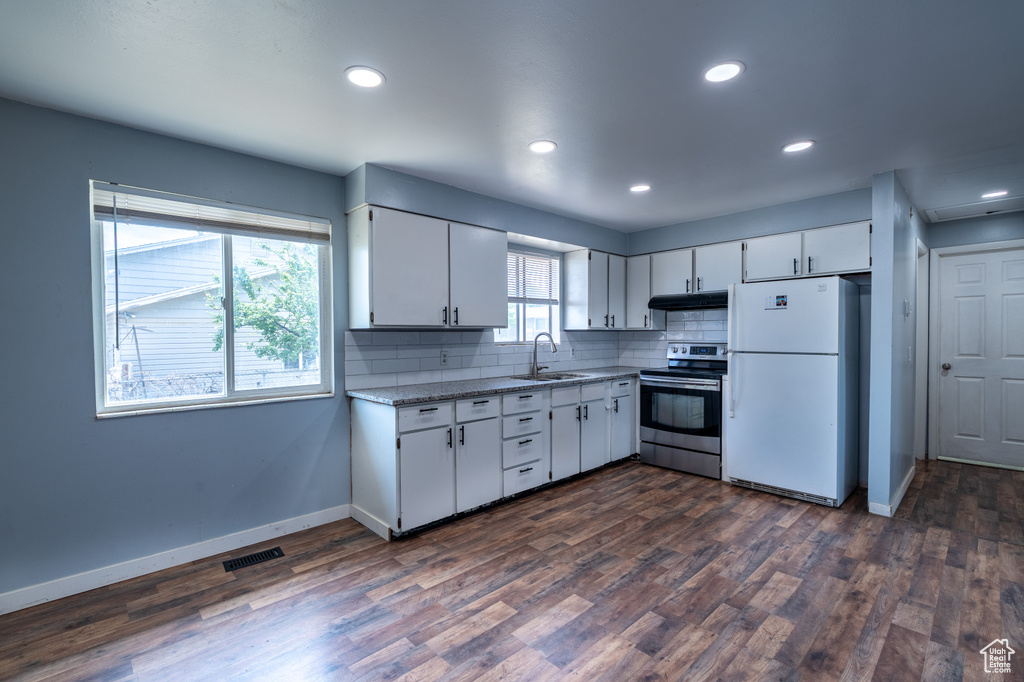 Kitchen featuring stainless steel electric range oven, freestanding refrigerator, a sink, under cabinet range hood, and baseboards