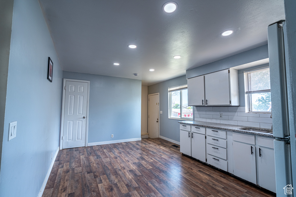 Kitchen with baseboards, recessed lighting, white cabinetry, dark wood-style flooring, and decorative backsplash