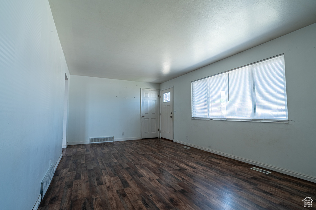 Empty room featuring dark wood finished floors and baseboards