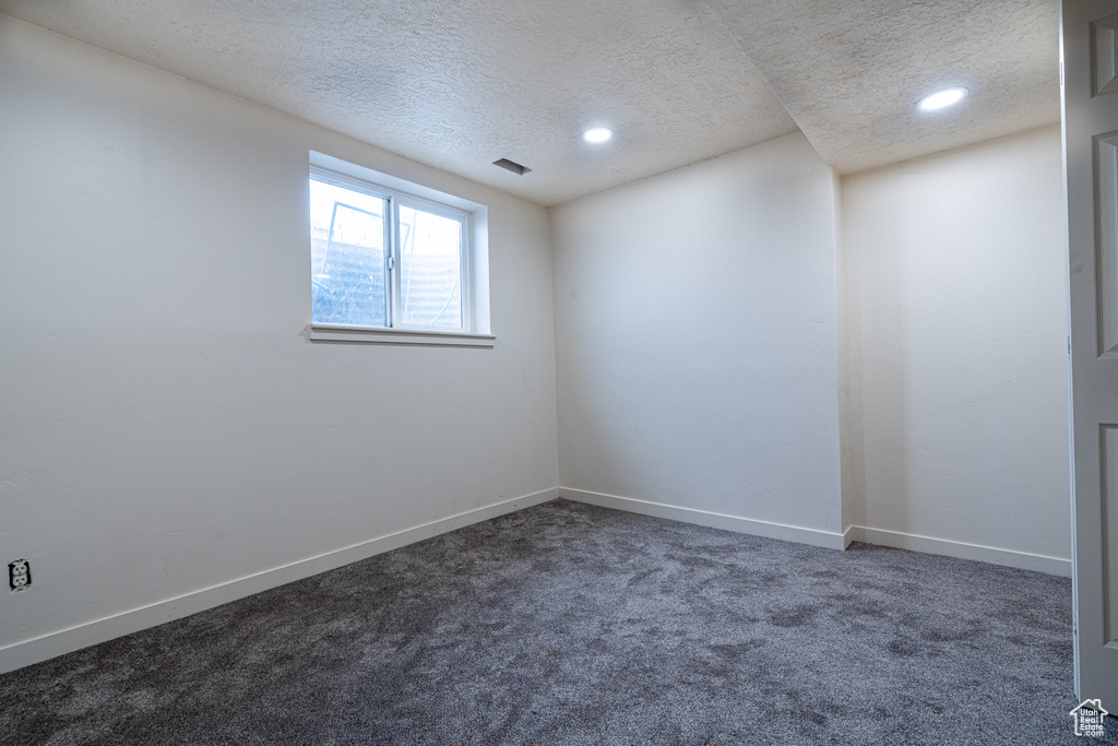 Spare room with a textured ceiling, dark colored carpet, recessed lighting, and baseboards