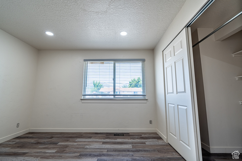 Unfurnished bedroom with a textured ceiling, dark wood-style floors, recessed lighting, and baseboards