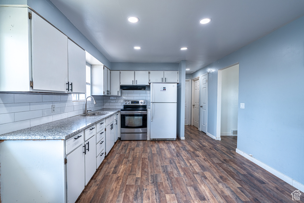 Kitchen with electric range, freestanding refrigerator, a sink, under cabinet range hood, and white cabinetry