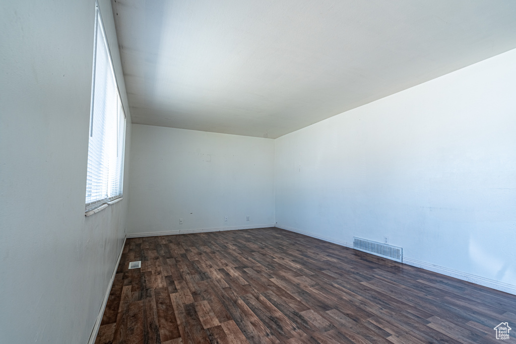 Unfurnished room featuring dark wood finished floors and baseboards