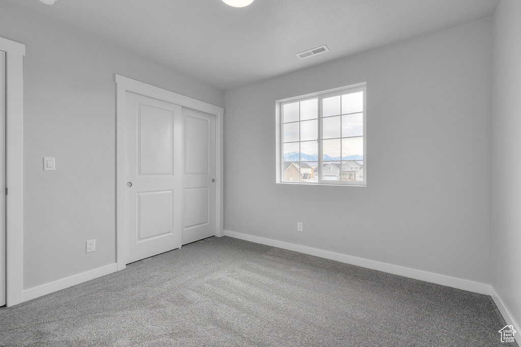 Unfurnished bedroom featuring carpet floors, baseboards, and a closet