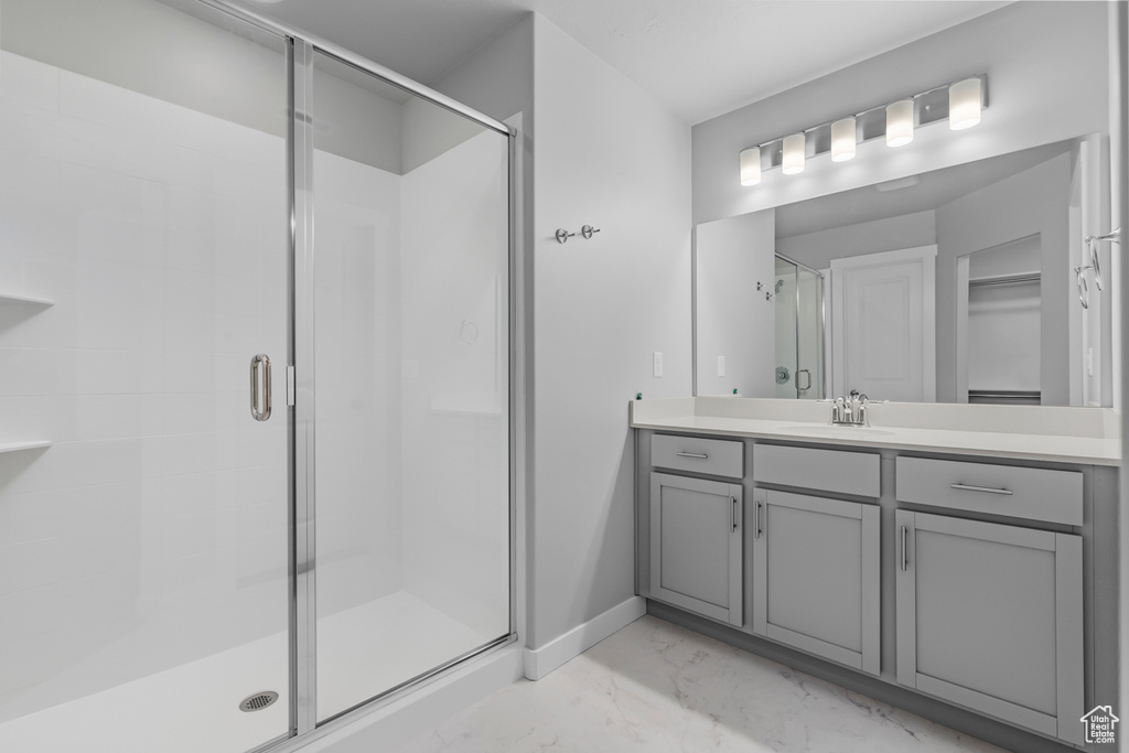 Bathroom featuring marble finish floors, vanity, a stall shower, baseboards, and a walk in closet