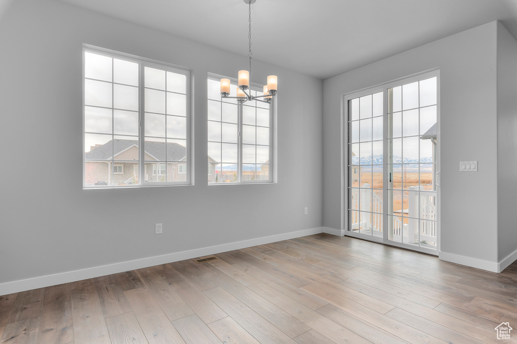 Spare room with a chandelier, baseboards, and hardwood / wood-style flooring