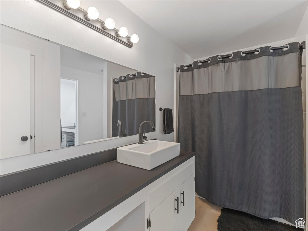 Full bathroom featuring vanity, wood finished floors, and a shower with curtain