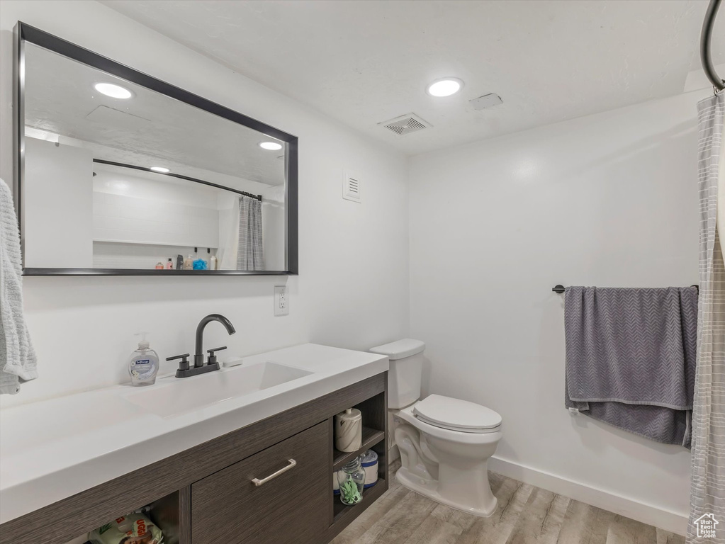 Bathroom featuring wood finished floors, vanity, toilet, recessed lighting, and curtained shower