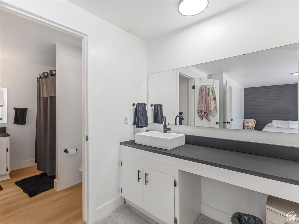 Full bathroom featuring vanity, wood finished floors, baseboards, and toilet