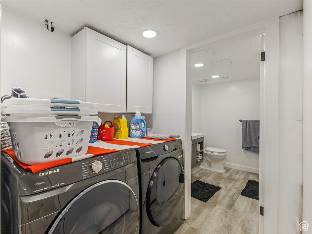 Laundry room featuring cabinet space, independent washer and dryer, light wood-style flooring, and baseboards
