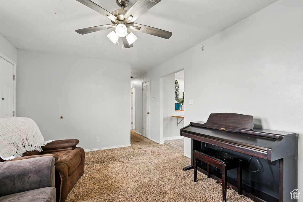 Sitting room featuring ceiling fan, baseboards, and light colored carpet