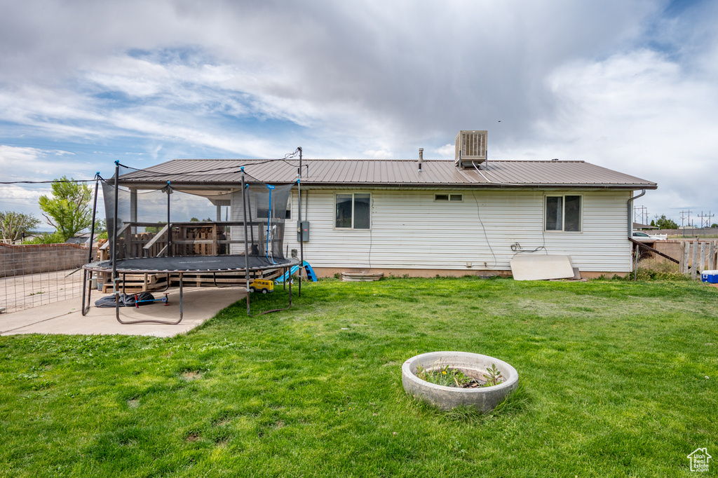 Rear view of property featuring a trampoline, metal roof, and a patio