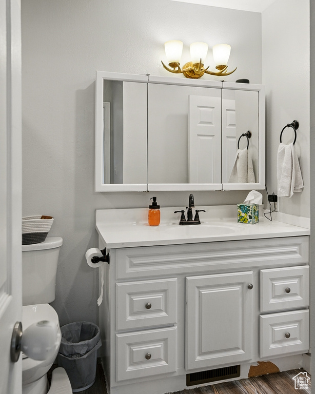 Bathroom with vanity, toilet, and wood finished floors