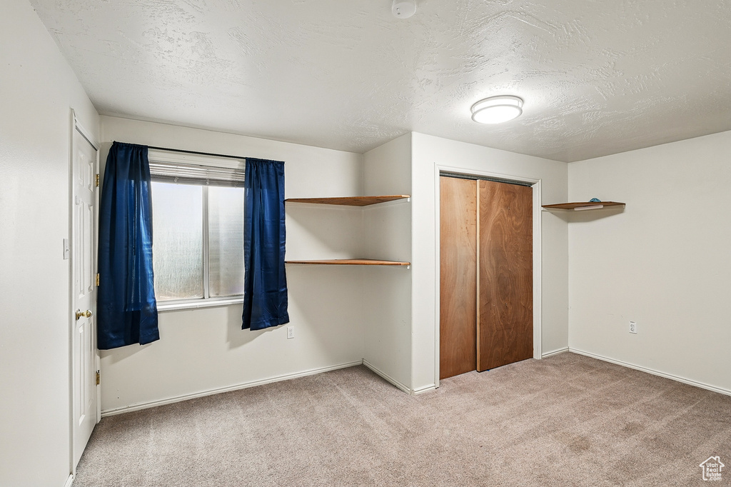 Unfurnished bedroom featuring carpet flooring, a closet, a textured ceiling, and baseboards