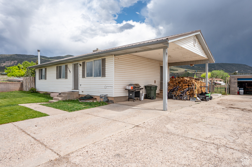 Rear view of property with an attached carport, concrete driveway, and a mountain view