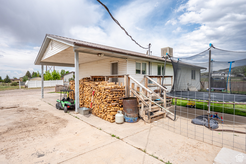 View of home's exterior with a trampoline, stairs, metal roof, and a patio